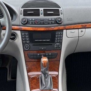 Mercedes E-Klasse W211 mit originalem Radio-Navigationssystem, seitlichen Bedientasten und Holzdekor in der Mittelkonsole.
