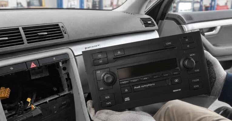 Ausgebautes Audi-Symphony-Werksradio mit CD- und Kassettenlaufwerk vor dem offenen Radioschacht.