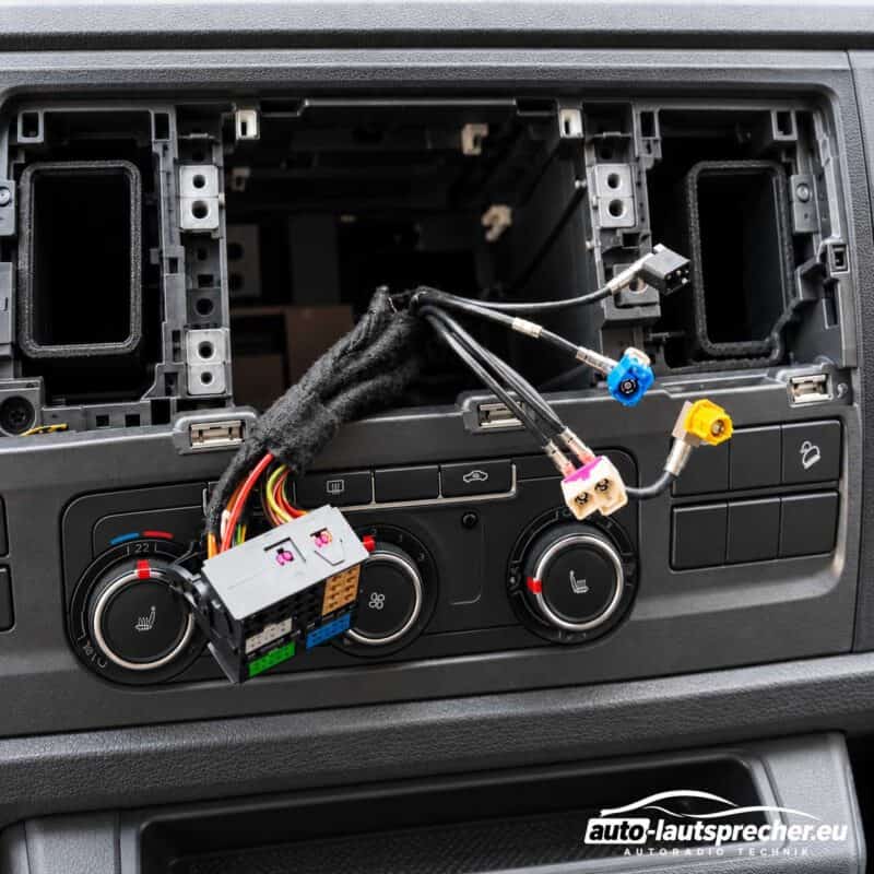 Geöffneter Radioschacht im VW T6 ab 2015 mit Fahrzeugkabelbaum, 52-Pin-Quadlockstecker und Anschlüssen für DAB+, AM/FM, GPS und USB.