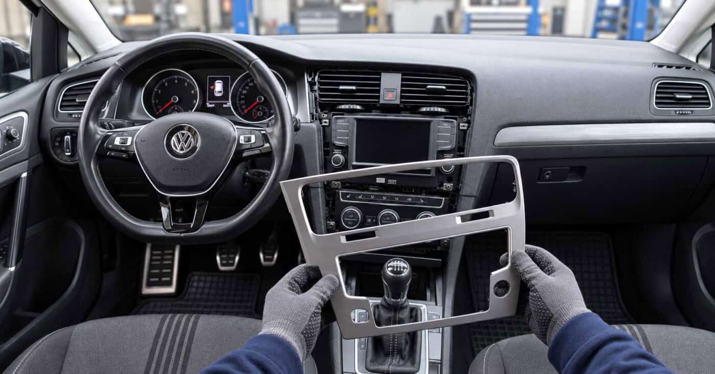VW Golf VII mit freigelegtem Radiodisplay und Klimabedienung; die abgenommene Verkleidung wird vor der Mittelkonsole gehalten.